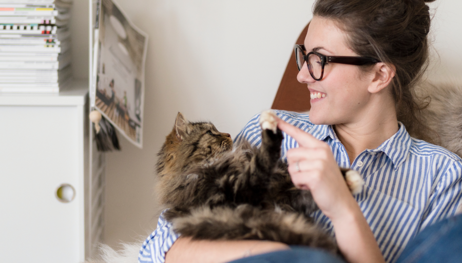 Žena seděla se svou kočkou na klíně a dotýkala se prstem její tlapky